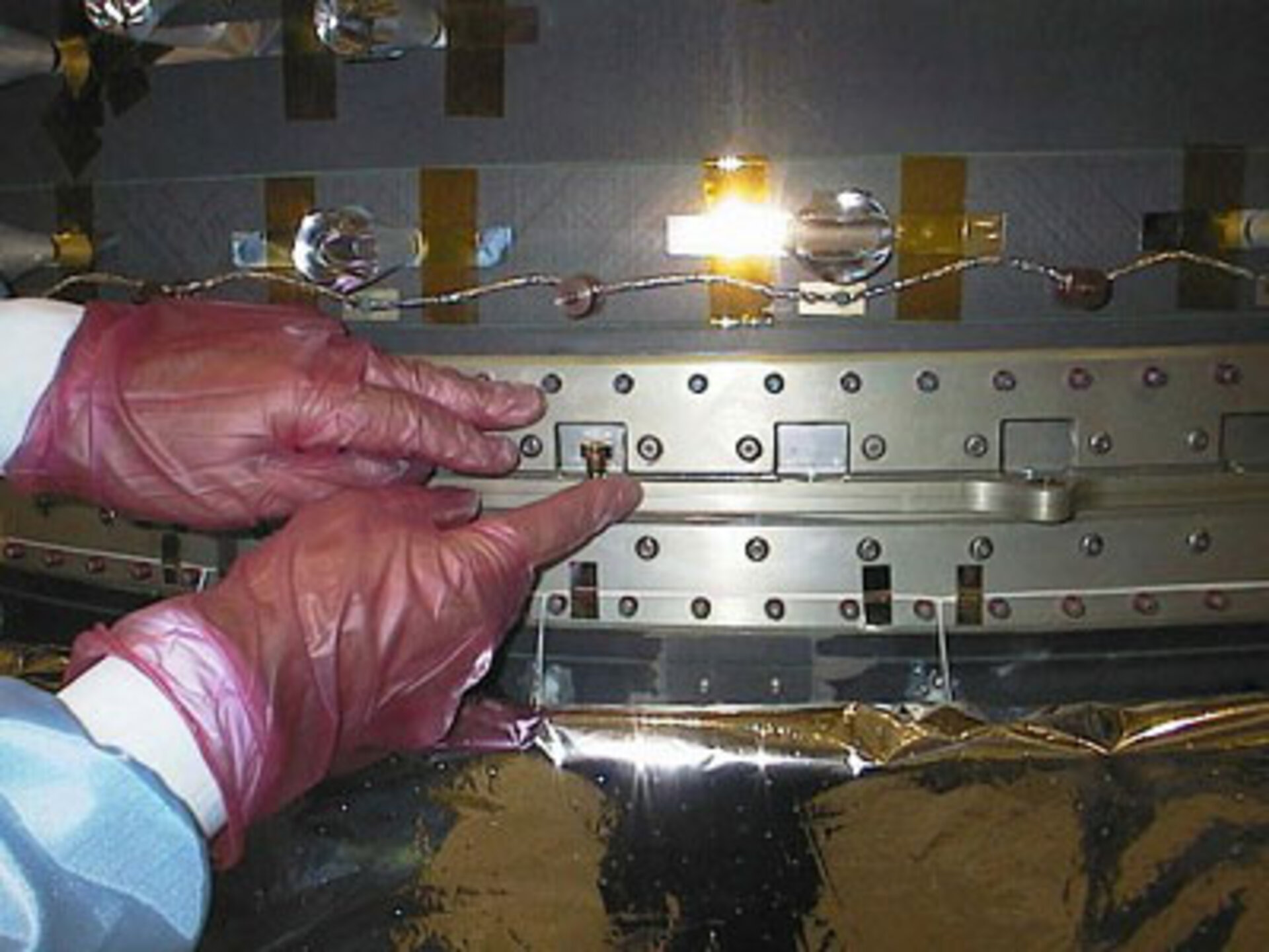 Technician fixing a golden bolt on XMM-Newton
