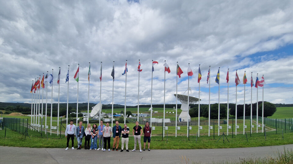 Students visiting the ESA ESEC-Redu site, surrounded by international flags and satellite antennas