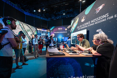 Participants listen on the exhibition floor at Living Planet Symposium 2025